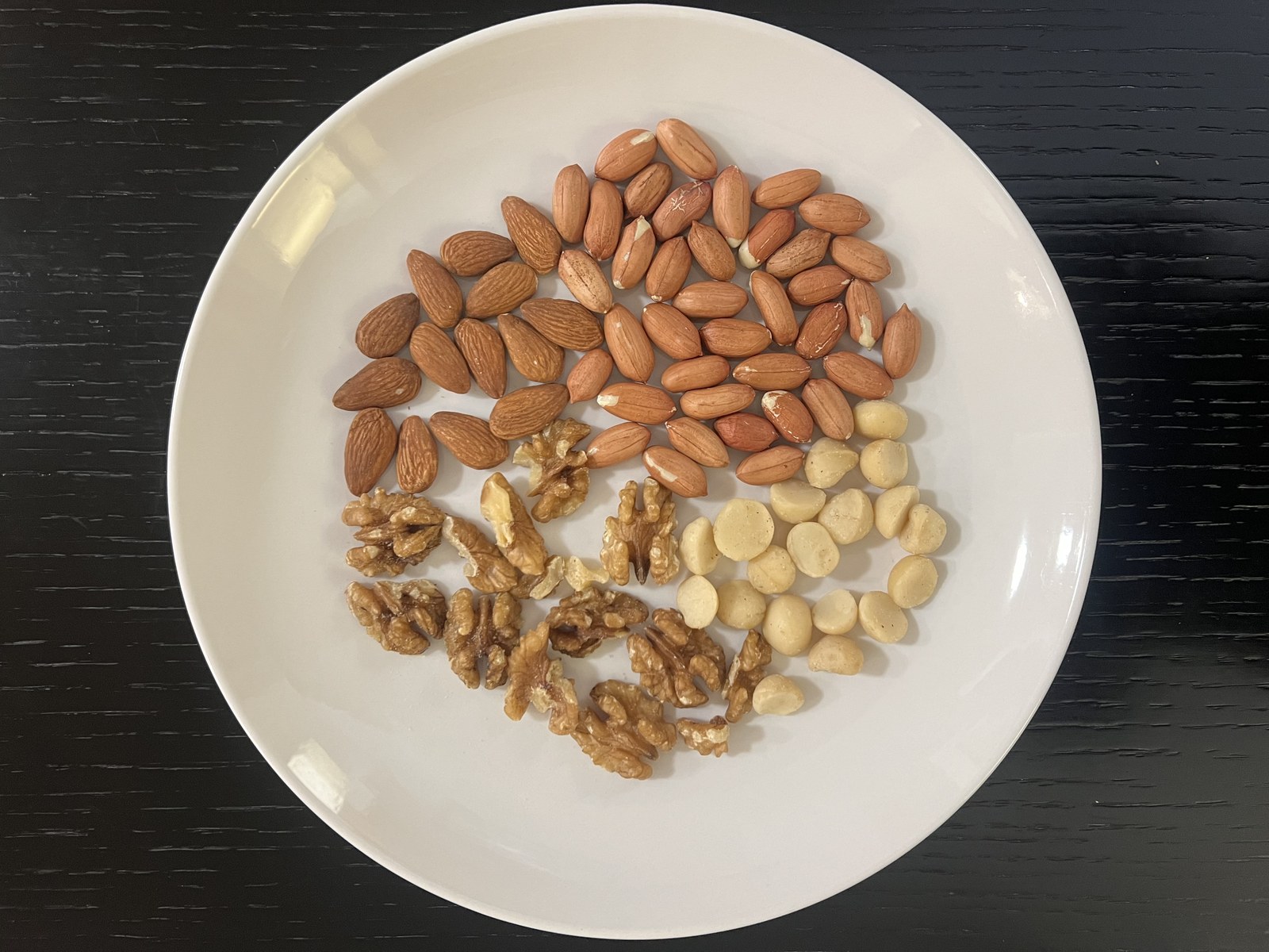 Real walnuts, almonds, peanuts and macadamia nuts arranged on a white plate - A Brand Under Sahaj Delight